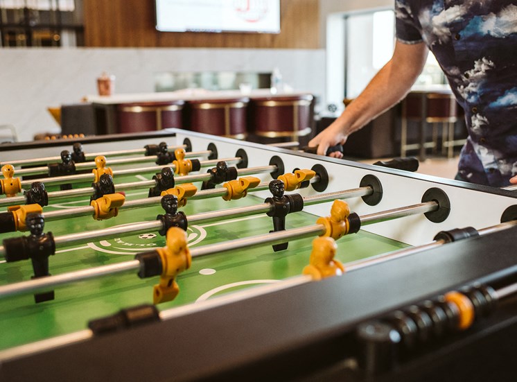 close up of a man playing foosball indoors